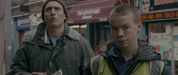 Movie still from “Wild Bill” (2011), directed by Dexter Fletcher – Two people standing next to each other on the sidewalk; Close Up shot, Over the shoulder angle