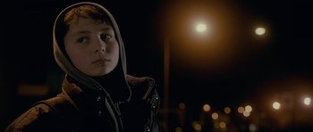 Movie still from “Wild Bill” (2011), directed by Dexter Fletcher – A young person wearing a hooded jacket standing in front of a street light; Close Up shot, Low angle