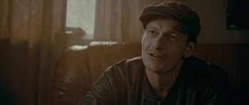 Movie still from “Wild Bill” (2011), directed by Dexter Fletcher – A person sitting on a couch wearing a hat; Close Up shot, Over the shoulder angle