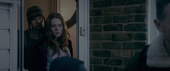 Movie still from “Wild Bill” (2011), directed by Dexter Fletcher – A woman standing in front of an open door; Medium shot, Over the shoulder angle