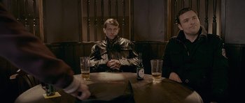 Movie still from “Wild Bill” (2011), directed by Dexter Fletcher – A man sitting at a table with two beers; Medium shot, Over the shoulder angle
