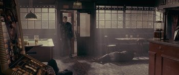 Movie still from “Wild Bill” (2011), directed by Dexter Fletcher – A man standing next to a dead body in a room; Wide shot, Low angle