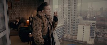 Movie still from “Wild Bill” (2011), directed by Dexter Fletcher – A woman smoking a cigarette while looking out of a window; Medium shot, High angle