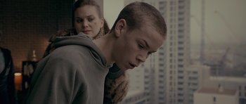 Movie still from “Wild Bill” (2011), directed by Dexter Fletcher – A young man with a shaved head looks out a window; Close Up shot, Over the shoulder angle