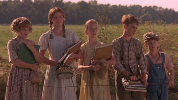 Movie still from “Wild Hearts Can't Be Broken” (1991), directed by Steve Miner – A group of people standing next to each other in a field; Medium shot, Low angle