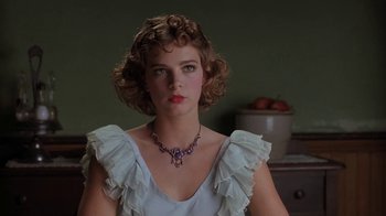 A woman wearing a white dress and a purple necklace