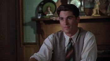 Movie still from “Wild Hearts Can't Be Broken” (1991), directed by Steve Miner – A man in a vest and tie sitting in front of a clock; Close Up shot, Over the shoulder angle