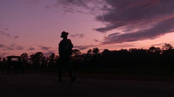 Movie still from “Wild Hearts Can't Be Broken” (1991), directed by Steve Miner – A man walking on a road at sunset; Wide shot, Low angle