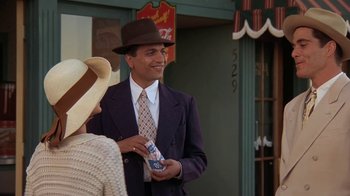 Movie still from “Wild Hearts Can't Be Broken” (1991), directed by Steve Miner – A man wearing a suit and tie holding a bottle of water; Medium shot, Low angle