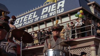 Movie still from “Wild Hearts Can't Be Broken” (1991), directed by Steve Miner – A man playing drums in front of a crowd of onlookers; Wide shot, Low angle