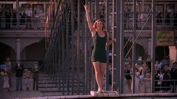 Movie still from “Wild Hearts Can't Be Broken” (1991), directed by Steve Miner – A woman in a black dress standing next to a metal structure; Wide shot, Low angle