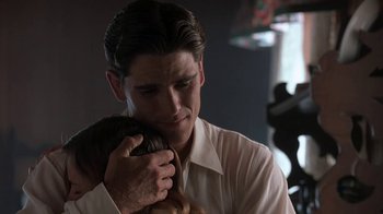 Movie still from “Wild Hearts Can't Be Broken” (1991), directed by Steve Miner – A man holding a woman in his arms in a dark room; Close Up shot, Over the shoulder angle