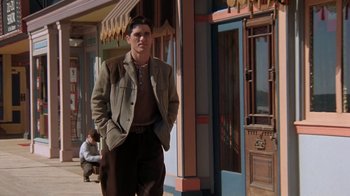 Movie still from “Wild Hearts Can't Be Broken” (1991), directed by Steve Miner – A man in a brown jacket standing in front of a building; Wide shot, Low angle