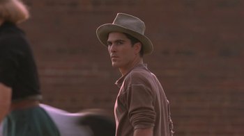 Movie still from “Wild Hearts Can't Be Broken” (1991), directed by Steve Miner – A man wearing a hat standing in front of a brick wall; Close Up shot, Over the shoulder angle