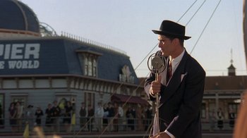 Movie still from “Wild Hearts Can't Be Broken” (1991), directed by Steve Miner – A man in a suit and hat holding a microphone; Medium shot, Low angle