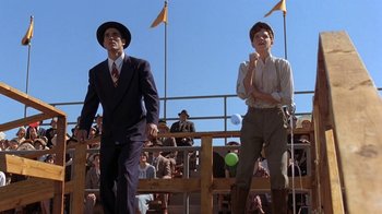 Movie still from “Wild Hearts Can't Be Broken” (1991), directed by Steve Miner – Two men in suits and hats are standing in front of a crowd of people; Wide shot, Low angle