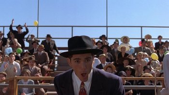 Movie still from “Wild Hearts Can't Be Broken” (1991), directed by Steve Miner – A man wearing a suit and hat in front of an audience; Medium shot, Low angle