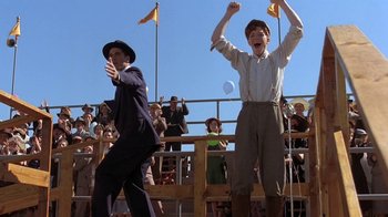 Movie still from “Wild Hearts Can't Be Broken” (1991), directed by Steve Miner – Two men are standing in front of an audience; Medium shot, Low angle