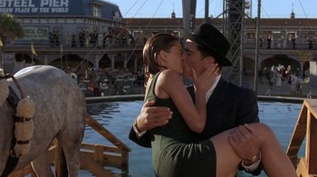 Movie still from “Wild Hearts Can't Be Broken” (1991), directed by Steve Miner – A man and a woman kissing in front of an ocean; Medium shot, Low angle