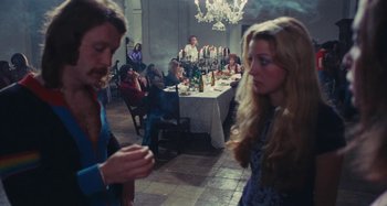 Movie still from “Your Vice Is a Locked Room and Only I Have the Key” (1972), directed by Sergio Martino – A group of people sitting at a table with food; Wide shot, Over the shoulder angle