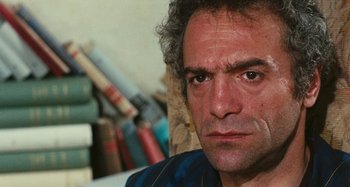 Movie still from “Your Vice Is a Locked Room and Only I Have the Key” (1972), directed by Sergio Martino – A man's face in front of books; Close Up shot, High angle