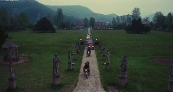 Movie still from “Your Vice Is a Locked Room and Only I Have the Key” (1972), directed by Sergio Martino – A couple of people on motorcycles on a dirt road; Extreme Wide shot, High angle