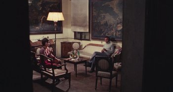 Movie still from “Your Vice Is a Locked Room and Only I Have the Key” (1972), directed by Sergio Martino – A man and a woman sitting on a couch in a living room; Wide shot, High angle