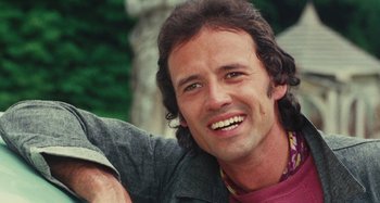 Movie still from “Your Vice Is a Locked Room and Only I Have the Key” (1972), directed by Sergio Martino – A person sitting down with a smile on his face; Close Up shot, Low angle