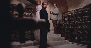Movie still from “Your Vice Is a Locked Room and Only I Have the Key” (1972), directed by Sergio Martino – A man standing in front of two women and a wine cellar; Wide shot, Low angle