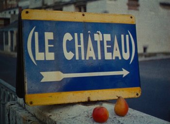 Movie still from “Ô saisons ô chateaux” (1958), directed by Agnès Varda – A blue and yellow sign on the side of the road; Extreme Close Up shot, Low angle