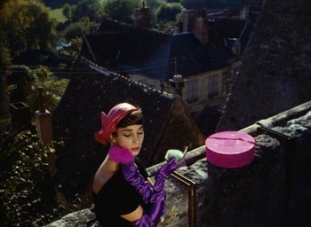 Movie still from “Ô saisons ô chateaux” (1958), directed by Agnès Varda – A woman in purple gloves and a hat on a balcony; Medium shot, Low angle
