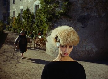 Movie still from “Ô saisons ô chateaux” (1958), directed by Agnès Varda – A woman wearing a fur hat standing on a street; Close Up shot, Low angle