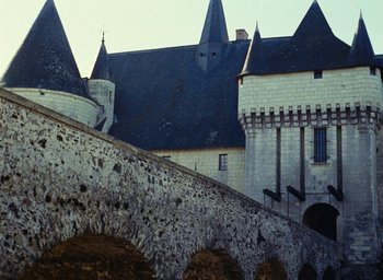 Movie still from “Ô saisons ô chateaux” (1958), directed by Agnès Varda – A castle like building with a stone wall and arches; Extreme Wide shot, High angle