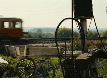 Movie still from “Ô saisons ô chateaux” (1958), directed by Agnès Varda – An old wooden wagon is in the foreground with train tracks in the background; Extreme Wide shot, Low angle