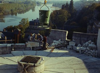 Movie still from “Ô saisons ô chateaux” (1958), directed by Agnès Varda – A group of people sitting on top of a stone wall; Extreme Wide shot, High angle