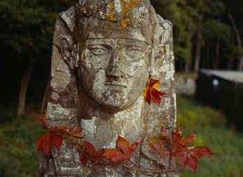 Movie still from “Ô saisons ô chateaux” (1958), directed by Agnès Varda – A statue of a man with a wreath around his neck; Close Up shot, Low angle
