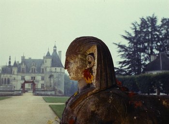 Movie still from “Ô saisons ô chateaux” (1958), directed by Agnès Varda – A statue of a woman in front of an old castle; Extreme Wide shot, Low angle