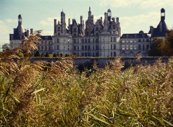 Movie still from “Ô saisons ô chateaux” (1958), directed by Agnès Varda – A castle with many windows and a large building with many towers; Extreme Wide shot, High angle