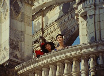 Movie still from “Ô saisons ô chateaux” (1958), directed by Agnès Varda – Two women in medieval garb standing on a balcony; Wide shot, Low angle