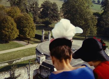 Movie still from “Ô saisons ô chateaux” (1958), directed by Agnès Varda – Two people standing in front of an outdoor structure; Extreme Wide shot, Overhead angle