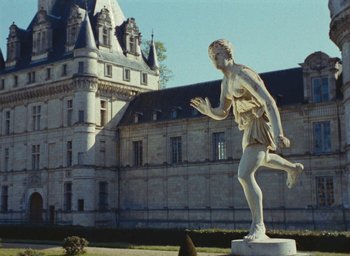 Movie still from “Ô saisons ô chateaux” (1958), directed by Agnès Varda – A statue in front of an old building; Extreme Wide shot, Low angle