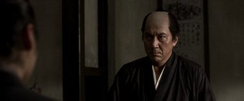 A man with a shaved head wearing a black robe