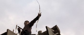 Movie still from “13 Assassins” (2010), directed by Takashi Miike – A man holding a bow and arrow up in the air; Medium shot, Low angle