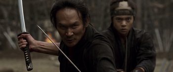 A man holding a bow and arrow while standing next to another man