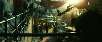 Movie still from “13 Hours” (2016), directed by Michael Bay – A group of people walking down a street next to cars; Extreme Wide shot, High angle