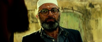 Movie still from “13 Hours” (2016), directed by Michael Bay – A man with a beard wearing glasses and a white hat; Close Up shot, Low angle