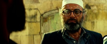 Movie still from “13 Hours” (2016), directed by Michael Bay – A man with a beard wearing glasses and a white hat; Close Up shot, Low angle