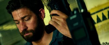Movie still from “13 Hours” (2016), directed by Michael Bay – A man is holding a cell phone up to his ear; Close Up shot, Low angle