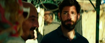 Movie still from “13 Hours” (2016), directed by Michael Bay – Two men standing next to each other in front of trees; Close Up shot, Over the shoulder angle