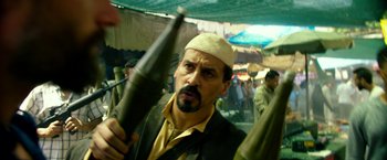 Movie still from “13 Hours” (2016), directed by Michael Bay – A man with a beard and a white hat holding a gun; Close Up shot, Over the shoulder angle